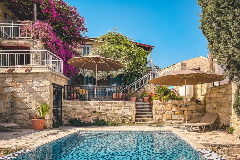 Kleiner Pool mit Fliesenmosaik, umgeben von Bougainvillea und zypriotischen Steinhäusern