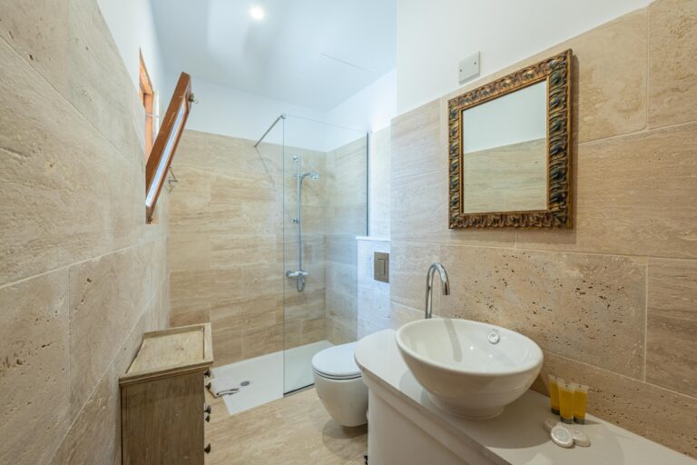 Badezimmer mit Glasdusche und Natursteinfliesen im traditionellen Stil