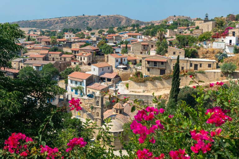 Blick auf das zypriotische Dorf Tochni mit Steinhäusern und sanften Hügeln im Hintergrund
